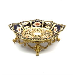 Edwardian Royal Crown Derby Imari pattern dish supported by a 19th century gilt metal stand decorated with floral swags on four Quiver & Arrow and Cherub moulded scroll feet, L23.5cm