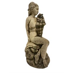 Composite stone garden ornament or water feature in the form of a nude maiden seated on rocks, holding a conch shell with water spout, on nauralist base