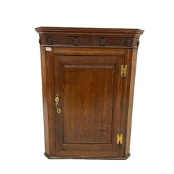Oak corner cupboard, the projecting cornice over carved frieze and one door, opening to reveal three fixed shelves 