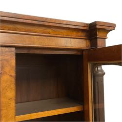 Victorian figured walnut enclosed bookcase, projecting cavetto cornice over two tall glazed doors, fitted with adjustable shelves, turned and fluted upright pilasters with lappet and guilloche carved decoration, on plinth base