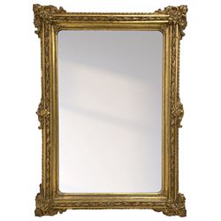 19th century giltwood and gesso wall mirror, the rectangular frame decorated with trailing fruiting foliage and C-scroll foliage cartouche corner brackets, plain mirror plate