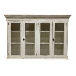 Painted pine wall cabinet, projecting cornice with dentil derail, fitted with four glazed doors enclosing four shelves, flanked by reeded pilasters, in cream finish