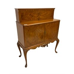 Mid-to-late 20th century figured walnut cocktail cabinet, raised upper section enclosed by hinged door, double cupboard below, the interior fitted with drawer and shelf, on acanthus carved cabriole supports 