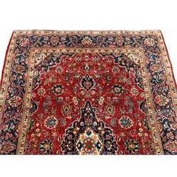 Small Persian Kashan crimson ground rug, indigo ground and floral decorated central medallion and spandrels, the field decorated with trailing branches and stylised plant motifs, repeating floral design border