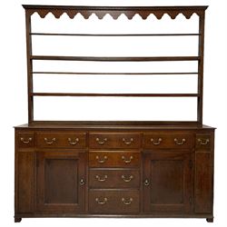 George III oak Yorkshire dresser and rack, the moulded cornice over a fretwork frieze and three-tier plate rack, the base fitted with four central graduating drawers flanked by two drawers over single panelled cupboard doors, the ends fitted with two small drawers over applied moulded panels, raised on stile feet