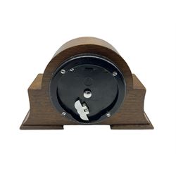 A small mid-20th century English made mantle clock in a round oak case with protruding side supports, Elliot spring driven eight-day drum movement wound and set from the rear, with a circular silvered dial, gilt baton hands, Arabic numerals and baton markers, within  a brass bezel and convex glass.  