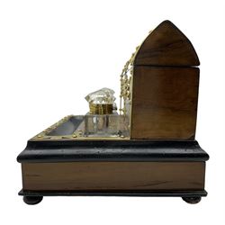 Victorian walnut and brass bound desk stand, the gothic cut brass mounts applied with stud work, hinged domed top enclosing a divided interior, two glass inkwells, ebonised pen rest above a single fitted drawer, on four bun supports, L30.5cm, H23cm, D23.5cm 