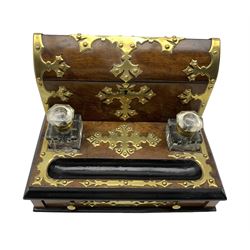 Victorian walnut and brass bound desk stand, the gothic cut brass mounts applied with stud work, hinged domed top enclosing a divided interior, two glass inkwells, ebonised pen rest above a single fitted drawer, on four bun supports, L30.5cm, H23cm, D23.5cm 