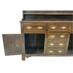 19th century Georgian design oak dresser, projecting cornice over shaped apron and three-tier plate rack, the base fitted with three cock-beaded frieze drawers over three central faux drawers, flanked by panelled cupboards, lower moulded edge over bracket feet