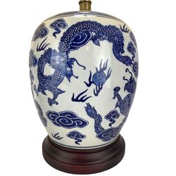 Pair of blue and white ovoid form table lamps, each decorated with dragons chasing the flaming pearl amidst clouds, raised upon circular hardwood bases, H28cm excluding fitting