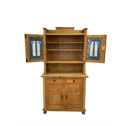 Pine dresser, the two glazed doors opening to reveal two fixed shelves over two drawers and cupboard doors, raised on turned turned bun feet 