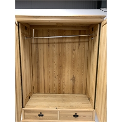 20th century stripped pine double wardrobe, projecting cornice over two panelled doors enclosing interior fitted for hanging, two drawers to base, raised on turned lobe carved front supports 