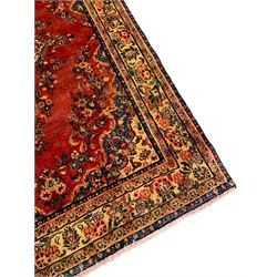 Persian crimson ground rug, the field with shaped central medallion and surrounding floral decoration, multiple band border, the main band decorated with repeating floral bouquets and trailing leafy branches