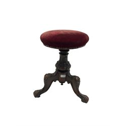 Victorian carved piano stool. the swivel seat upholstered in red fabric over carved column leading into three carved supports H50cm