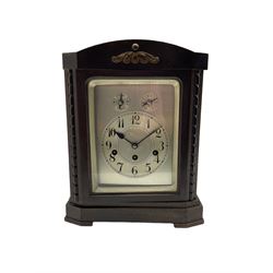 Juhngans - 20th century German 8-day Westminster chiming mantle clock in a ebonised finished wooden case, spring driven  three train movement sounding the quarters and hours on 4 gong rods, with a silvered dial plate, chapter ring, Arabic numerals and minute track, subsidiary dials for pendulum regulation and chime/silent facility, glazed door with a silvered slip. With pendulum and key.