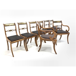 Set eight Regency beech dining chairs, shaped crest rail with inlaid brass foliate decoration, pierced carved rail cantered by brass inlaid roundel, drop in upholstered seat pad, raised on sabre supports 