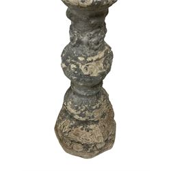 Pair of 20th century composite stone candle stands, with pressed metal collars or candle sconces in the form of splayed leaves, the pedestals cast with acanthus leaves and flower head decoration