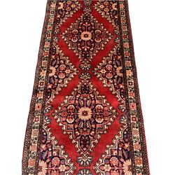 Persian crimson ground runner, the field decorated with seven floral lozenges with plain red borders, the triple-band ivory border with repeating flower head and foliate motifs