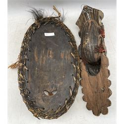  Papua New Guinea Sepik River mask of elongated oval form, brown and white pigment and cowrie shells 49cm x 28cm and another with black, orange, pink and white pigment 46cm x 15cm