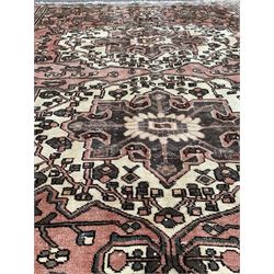 Vintage Persian faded red ground rug, with double medallion on floral field, geometric foliate to border 254cm x 157cm