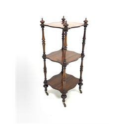 Small Victorian rosewood three tier whatnot, with turned finials, serpentine shelves, raised on turned supports and brass castors, 