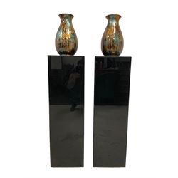 Pair of black bevelled acrylic stands, with vases