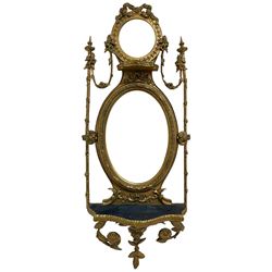Victorian ornate gilt gesso framed mirror, pierced ribbon bow pediment with trailing foliate border atop the small bevelled mirror plate, acanthus leaf and foliate swags connect to the spear-topped uprights adorned with further foliate decoration, the main oval bevelled plate with a foliate and beaded frame connected to the smaller with a candle shelf, a larger serpentine shelf below the larger mirror plate with a trailing laurel leaf base with flowerheads