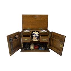 Early 20th century oak smokers cabinet, containing various pipes, tobacco jar, mixing bowls etc, W38cm together with an oak tapestry fire screen, H78cm (2)
