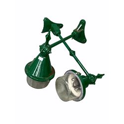 Near pair of green painted cast iron street lights with domed glass lampshades and concave wall brackets, one stamped 'ELECO' and one 'REVO' 