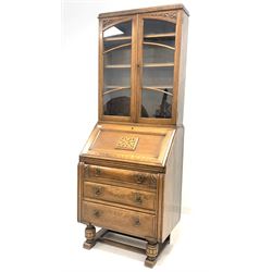 Early 20th century oak bureau bookcase, the top section with dentil cornice over two glazed doors enclosing three adjustable shelves, fall front under revealing fitted interior, three drawers to base, raised on turned front supports on sledge feet united by stretcher W75cm, H195cm, D48cm