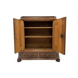 19th century walnut cupboard, carved with foliage scrolls, masks and ribbons and fitted with one cushion drawer over two cupboard doors opening to reveal two fixed shelves and one long drawer, raised on ball and claw feet 