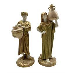 Pair of Royal Worcester porcelain figures modelled as male and female water carriers, dressed in green-gilt robes standing on a rocky ground, date marked 1913, shape 1250, H24.5cm 