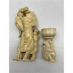19th/ early 20th century Japanese ivory Okimono modelled as a farmer and his Son, the Farmer carrying a basket of lotus flowers, H16.5cm together with an early 20th century Chinese carved bone puzzle ball stand in the form of a Toad (2)