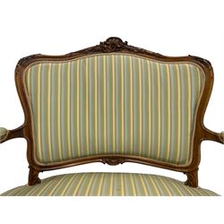 Late 20th century French walnut settee, the shaped cresting rail carved with foliate scroll cartouche and trailing foliage, upholstered back, arms and sprung serpentine seat in striped fabric, shaped apron carved with c-scroll cartouche, moulded cabriole supports