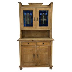 Pine dresser, the two glazed doors opening to reveal two fixed shelves over two drawers and cupboard doors, raised on turned turned bun feet 