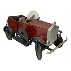 Retailed by Hamley's - 1960s/70s child's sit on Rolls Royce car, wood and metal construction with leather seat, in burgundy paint finish with gold pin striping, fitted with fold down luggage rack, faux dials, single wingmirror, spare wheel and hinged bonnet cover, with plaque inscribed 'Hamley's, 200-202. Regent Street. London'