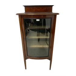 Edwardian mahogany bow front music or display cabinet, raised back with inlaid satinwood garlands and stringing, glazed cupboard door enclosing three shelves, raised on square tapering supports 
