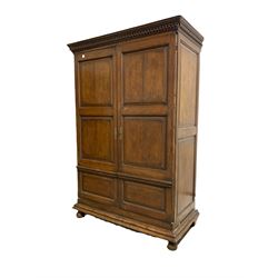 18th century and later oak housekeepers cupboard, dentil cornice over two fielded panelled doors enclosing interior fitted for hanging, raised on a moulded plinth base with bun supports, formerly a press W1330cm, H197cm, D65cm