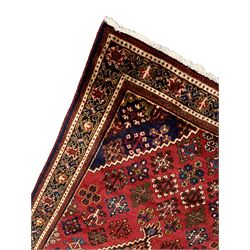 Persian Joshagan crimson ground rug, the field with a central lozenge medallion, surrounded by stylised tree of life and floral motifs with contrasting indigo spandrels, the guarded border with repeating scrolling palmettes