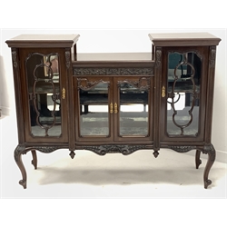 Early 20th century Georgian style mahogany display cabinet, having an incised frieze decorated with scrolled foliate over four glazed cupboard doors enclosing bevelled mirrored back and silk lined shelves, floral and shell carved serpentine apron, all raised on slender cabriole supports 