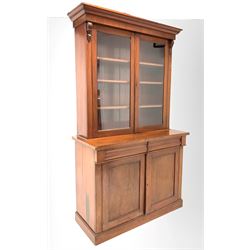 Victorian mahogany bookcase on cupboard, the top section fitted with two glazed doors enclosing three adjustable shelves, two cushion fronted frieze drawers and two panelled doors under, enclosing twelve drawers, raised on plinth base W123cm, H215cm, D53cm