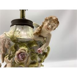 Sitzendorf ceramic table lamp base, decorated with applied cherubs, foliage and roses upon three feet, converted to electricity H27cm