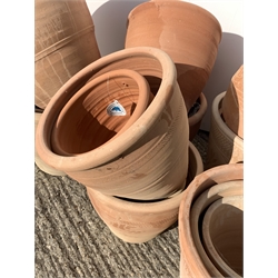 Twenty five circular terracotta plant pots, various sizes, some decorated with stars,