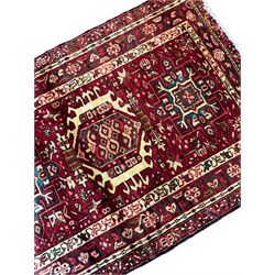 Persian Karajeh red ground runner rug, the field decorated with seven central rectilinear medallions surrounded by geometric patterns, the multi-band border with repeating stylised plant motifs with geometric foliage