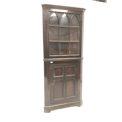 Early 19th century mahogany floor standing corner cupboard, dentil cornice over gothic arched astragal glazed doors enclosing two shelves, four panelled door under, raised on bracket supports, W77cm, H180cm, D40cm
