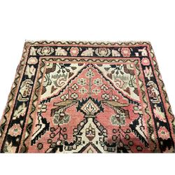 Persian rose ground runner rug, the field decorated with three floral medallions with dark indigo outlines, surrounded by stylised flower and urn motifs, guarded border with repeating foliate patterns