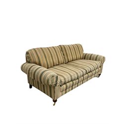 Traditional three seater sofa, with loose cushions upholstered in striped fabric, raised on turned supports terminating in brass castors W210cm
