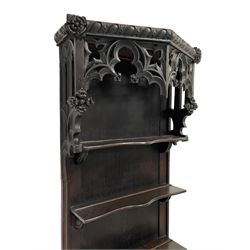 18th century and later Gothic Revival walnut and oak narrow dresser, the projecting pierced tracery canopy with egg and dart carved edge decorated with applied roses, over a three-tier plate rack, the base with a rectangular walnut top with feather banding, the edge carved with repeating anthemion decoration, the single cupboard door applied with gothic tracery and acanthus leaf moulded edge, enclosing two shelves