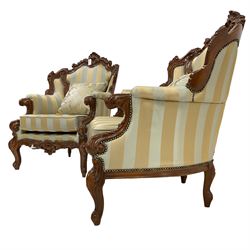 Pair Italian Rococo style carved walnut finish wingback armchairs, pierced cartouche pediment with scrolling, back and seat upholstered in blue and gold fabric with studwork, scrolled hand rail raised by foliate scrolled uprights and cabriole supports