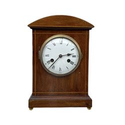 An early 20th century German mantle clock by Philipp Haas & Söhne, in a mahogany case with a curved top and inlay, white enamel dial with roman numerals and minute track, steel spade hands with a brass bezel and convex glass, eight-day movement sounding the hours and half hours on a coiled gong, with pendulum.




